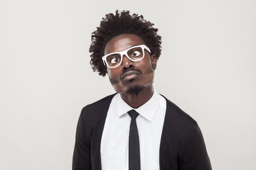 Portrait choke man in white glasses grimacing at camera. Studio shot, gray background
