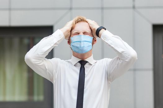 Bad emotions and feelings concept. Headache. Businessman with surgical medical mask touching head and have a migraine or problem with work. Outdoor shot. business, working and health care concept.