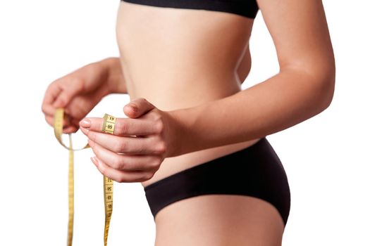 Slim fit happy young woman with measure tape measuring her waist with black underwear, isolated on white background. studio shot.