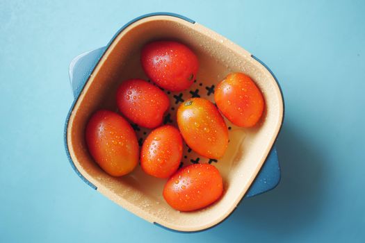cleaning fresh tomato with a water in a plastic bowl ,