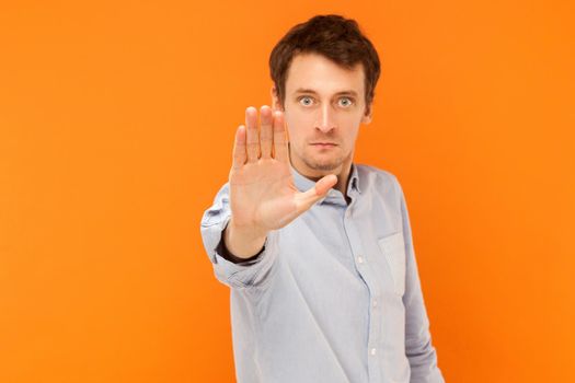 Stop hand. Focus on hand. Body language. Studio shot, orange background