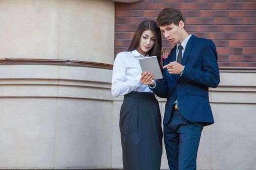 Business people using a digital tablet outdoor. Businessman and Businesswoman standing friendly on steps and using tablet with smile in the city.