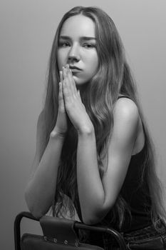 Beautiful woman looking at camera and pray or wish. Studio shot, isolated on gray background