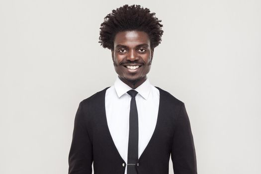 Happiness well dressed afro businessman looking at camera and toothy smiling. Studio shot, gray background