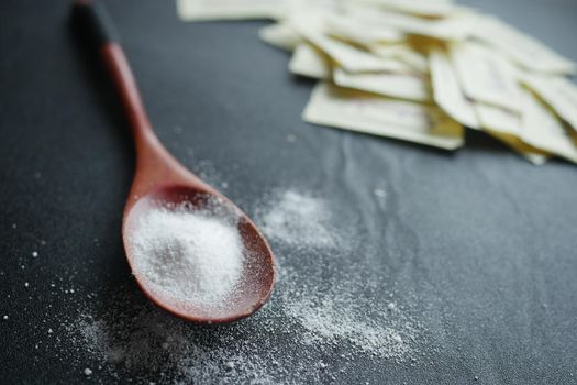 spoon of white sweetener on a black background