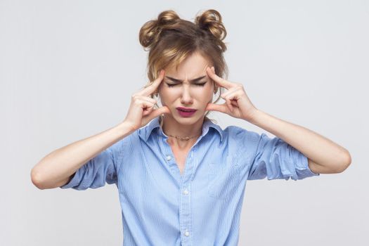 Bad emotions and feelings concept. Blonde woman touching head fingers and have a migraine. Studio shot, gray background