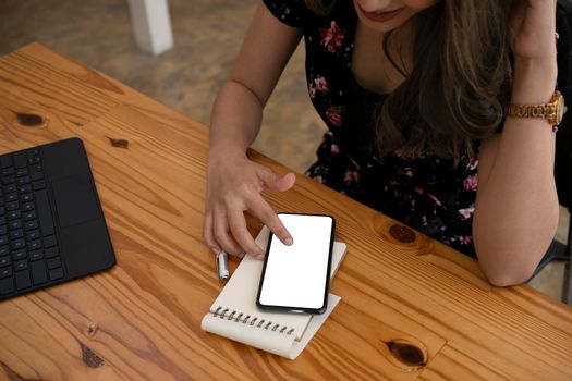 Young female office worker sitting in office and using smart phone.