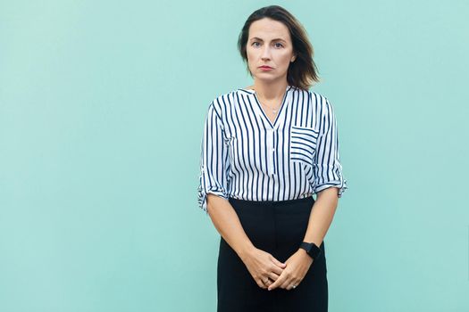 Unhappy business woman looking at camera with tired face. Isolated on light blue background