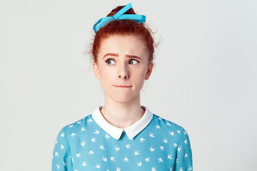 Hmm. Let me think. isolated studio shot on gray background of cute redhead girl with looking sideways and planning something.