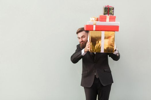 Funny man hiding behind boxes and looking at camera. Studio shot. Isolated on gray background