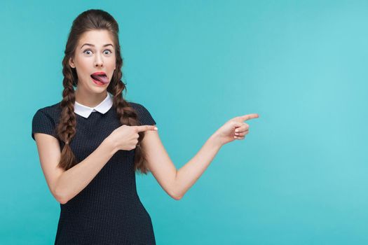 Crazy woman pointing finger at copy space. Studio shot, blue background