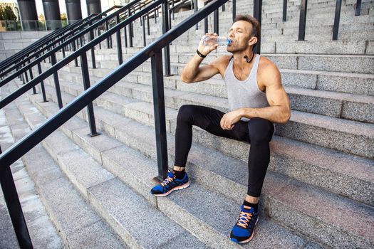 Thirsty sportsman take a rest and drinking water after running. fitness, sport, exercising and people healthy lifestyle concept.