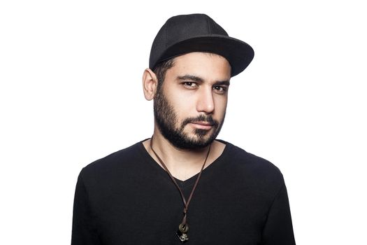 Portrait of young middle eastern man with black t-shirt and cap looking at camera. studio shot, isolated on white background.