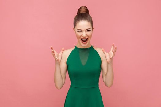Roar! Angry woman shouting at camera with rage. Expression emotion and feelings concept. Studio shot, isolated on pink background
