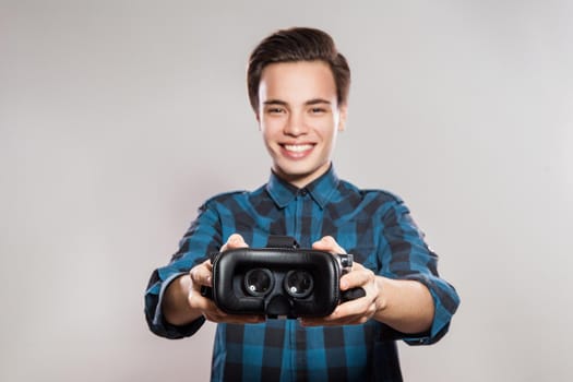 Portrait of young man with virtual reality headset. indoor, isolated on gray background.