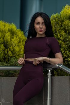 Portrait of a fitness girl in fashionable sportswear on the background of a shopping center building. Lifestyle, culture of a well-groomed female body.