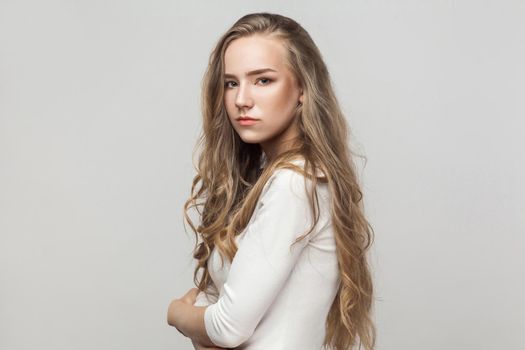 Fashion model looking at camera with passion, and posing sensual. Studio shot, gray background