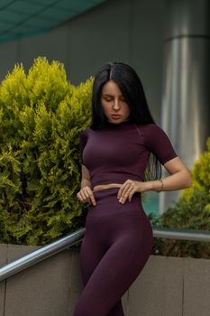 Portrait of a fitness girl in fashionable sportswear on the background of a commercial building. Lifestyle, culture of a well-groomed female body.