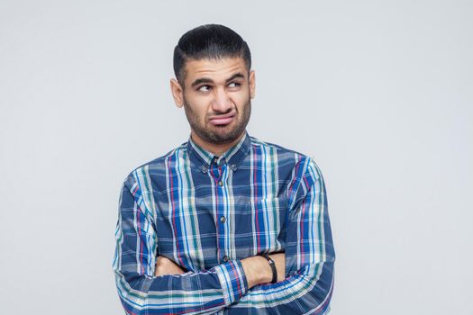 Indoor isolated studio shot on gray background of man looking away, having doubtful and indecisive face. Studio shot. Isolated on gray background