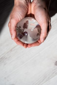 Close-up of female hands with a crystal globe on a woody background