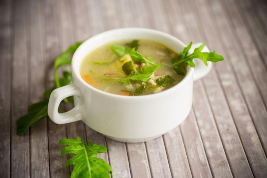 summer light soup with oatmeal and arugula in a plate on the table