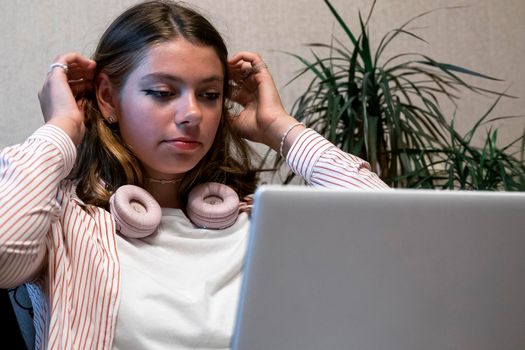 caucasian happy cute girl with headphones is using a laptop. Watch movies online. Distance education. Video call. Video chat with your family