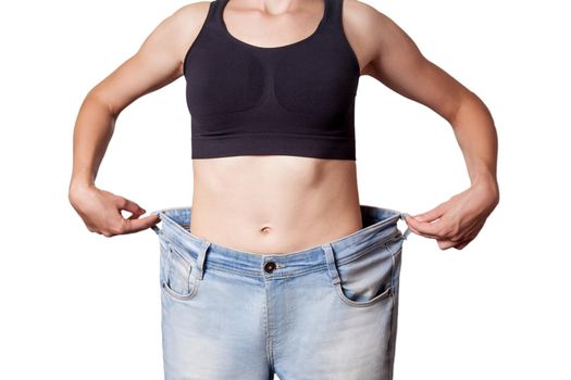 Close-up of slim waist of young woman in big jeans showing successful weight loss, isolated on white background, diet concept.