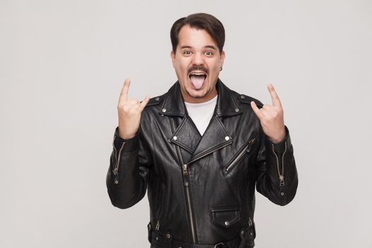 Rock and roll baby! Happines adult man toothy smiling with big eyes and showing rock sign. Indoor shot