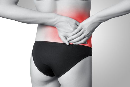 Closeup view of a young woman with pain in back on gray background. Black and white photo with red dot.