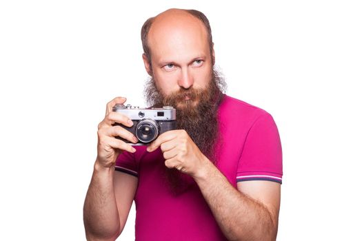The portrait of bald bearded man photographer with pink t shirt holding classic camera. isolated on white background. studio shot.