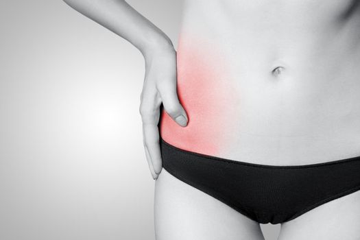 Closeup view of a young woman with pain in kidneys on gray background. Black and white photo with red dot.