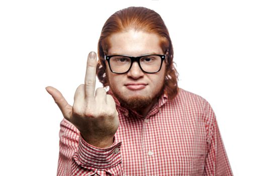 Angry bearded readhead businessman with red shirt and freckles looking at camera and showing middle finger . studio shot isolated on white.