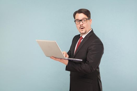 Business, gadgets,technologies. Man in shok. Holding note book. Indoor, studio shot, isolated on light blue or gray background