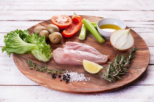 Ingredients for vegetable salad with chicken breast on a wooden plate. Stock image.