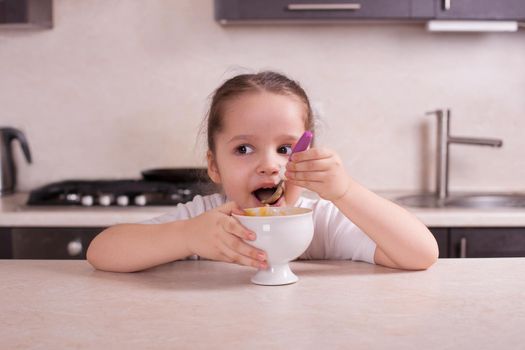 Girl eating in the kitchen soup from a pumpkin. Stock image.