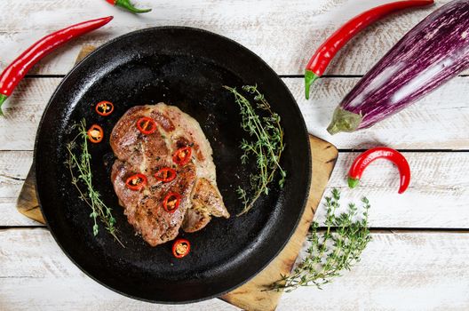 Cooking a steak in a frying pan with thyme and chilli. Stock image.