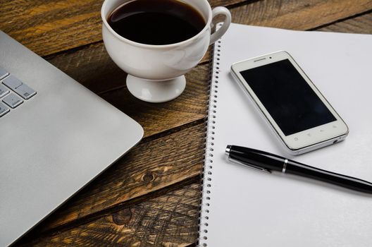 Cup of coffee and laptop on wooden table. Stock image.