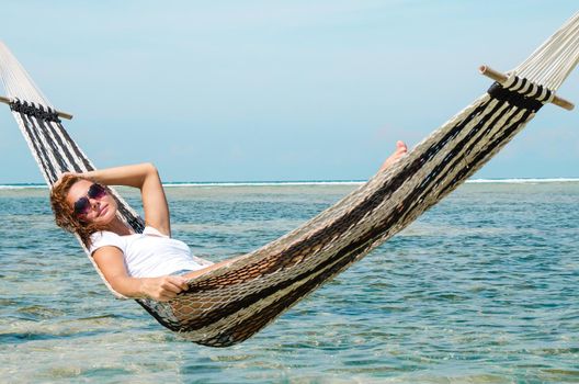 Girl relaxing in hammock on the beach near blue ocean. Bali, Indonesia. Stock image.