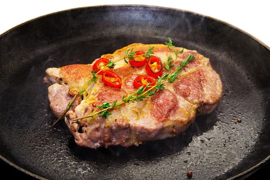 Cooking a steak in a frying pan with thyme and chilli. Stock image.