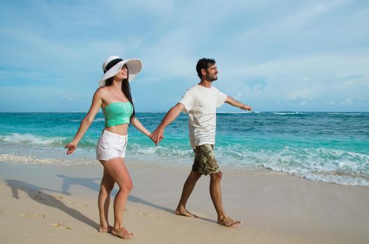 A loving couple walks on the azure beach. Stock image