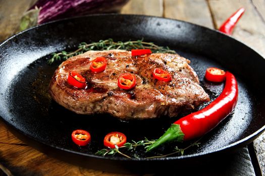 Cooking a steak in a frying pan with thyme and chilli. Stock image.