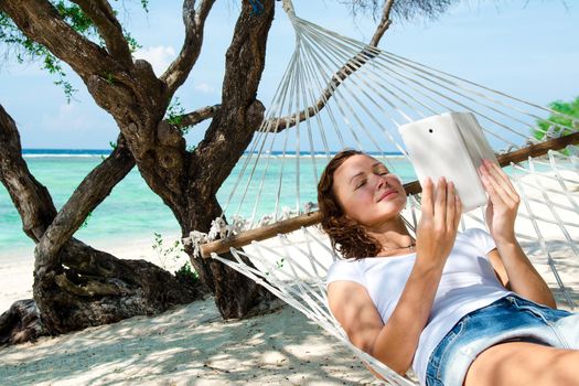 Woman in a hammock with laptop at the beach. Bali, Indonesia. Stock image.