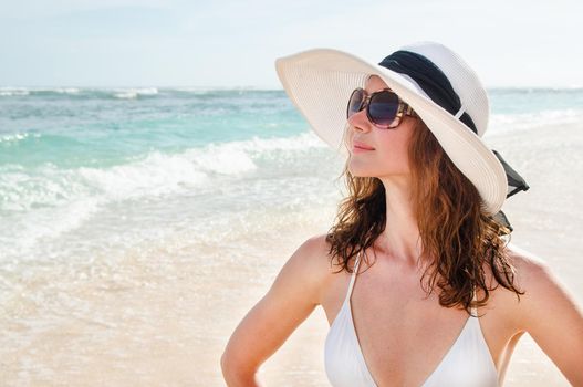 Young woman in a hat walking on the azure beach Bali. Stock image.