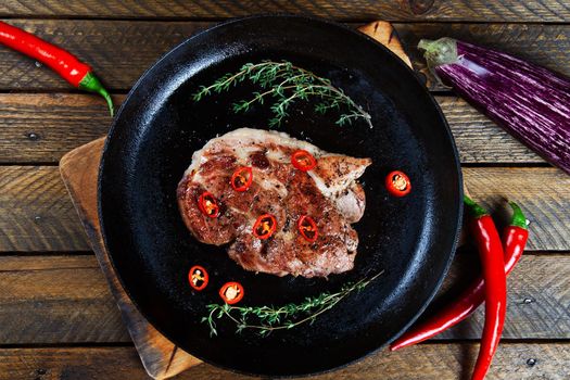 Cooking a steak in a frying pan with thyme and chilli. Stock image.