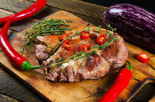 Cooking steak with thyme and chili pepper on a cutting board. Stock image.