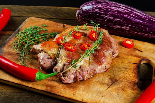 Cooking steak with thyme and chili pepper on a cutting board. Stock image.