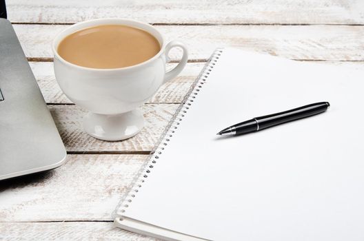 Cup of coffee and laptop on wooden office table. Stock image.