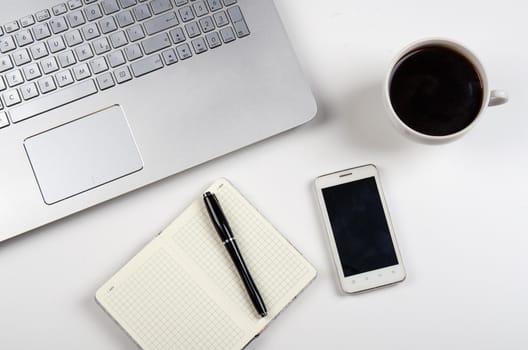 Cup of coffee and laptop on white table. Stock image.