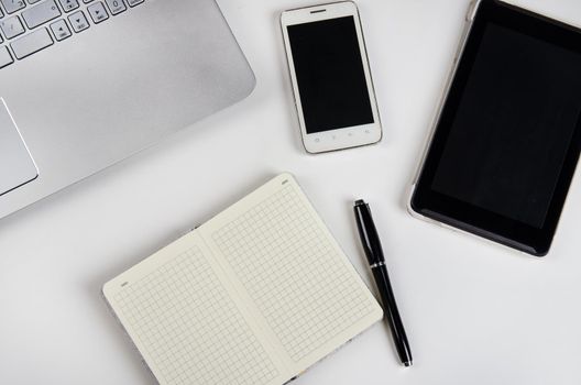 Laptop and notebook on a white table. Stock image.