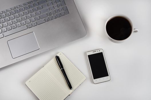 Cup of coffee and laptop on white table. Stock image.